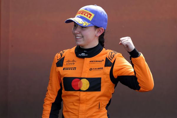 Race car driver in orange suit celebrating.