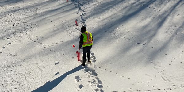 Technician performing private line locate on an excavation site in winter.