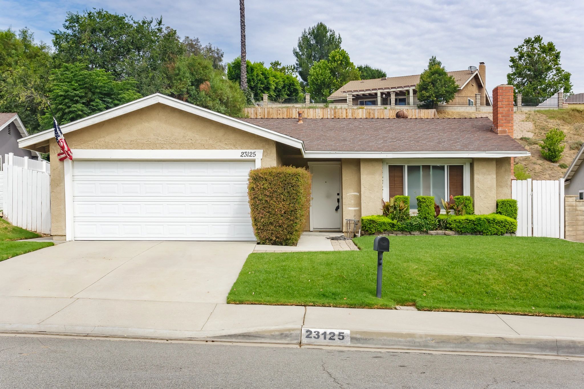 Single-story beige house with a white garage door and green lawn.