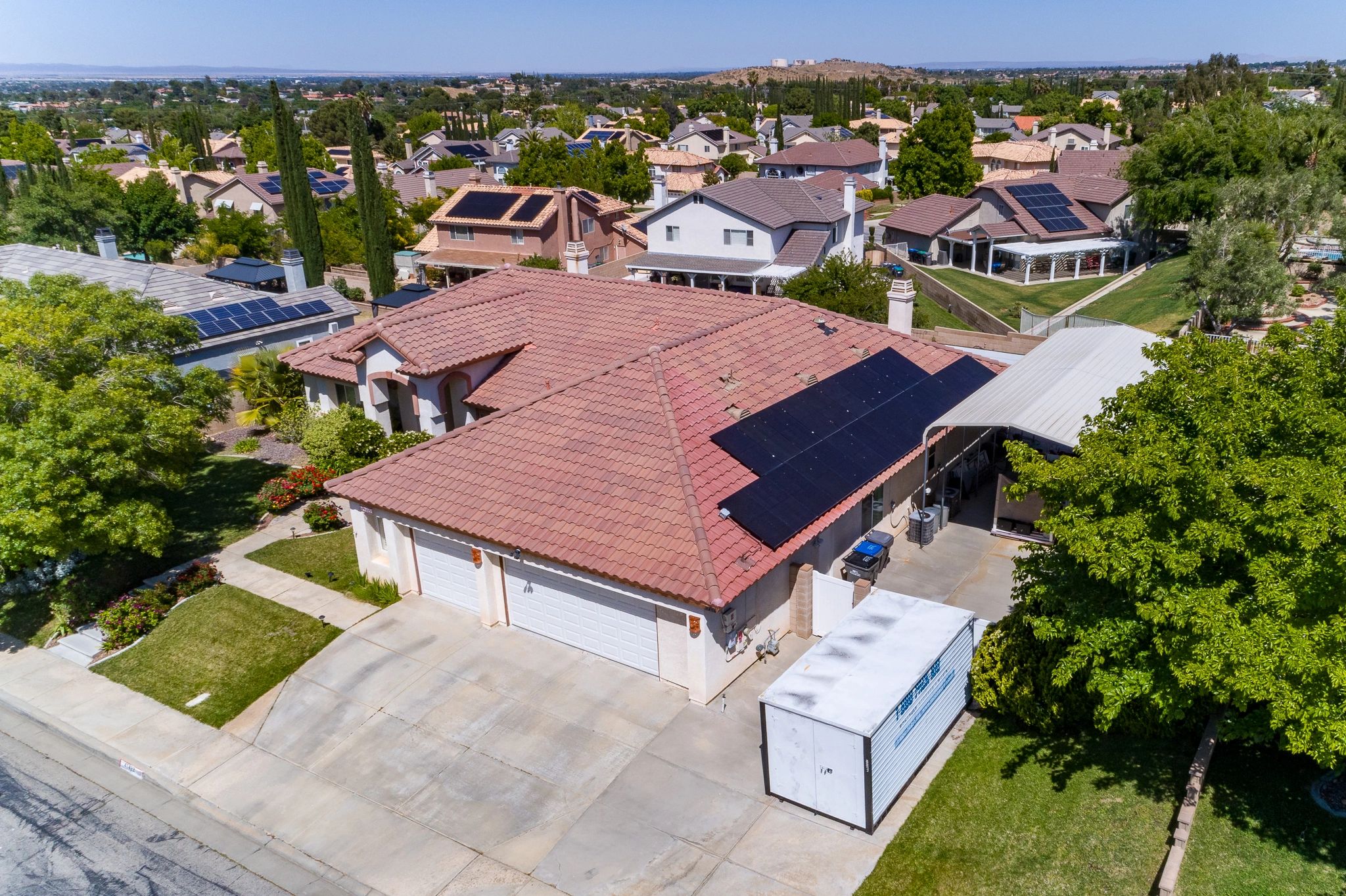 Suburban neighborhood with solar panels on roofs and lush greenery.