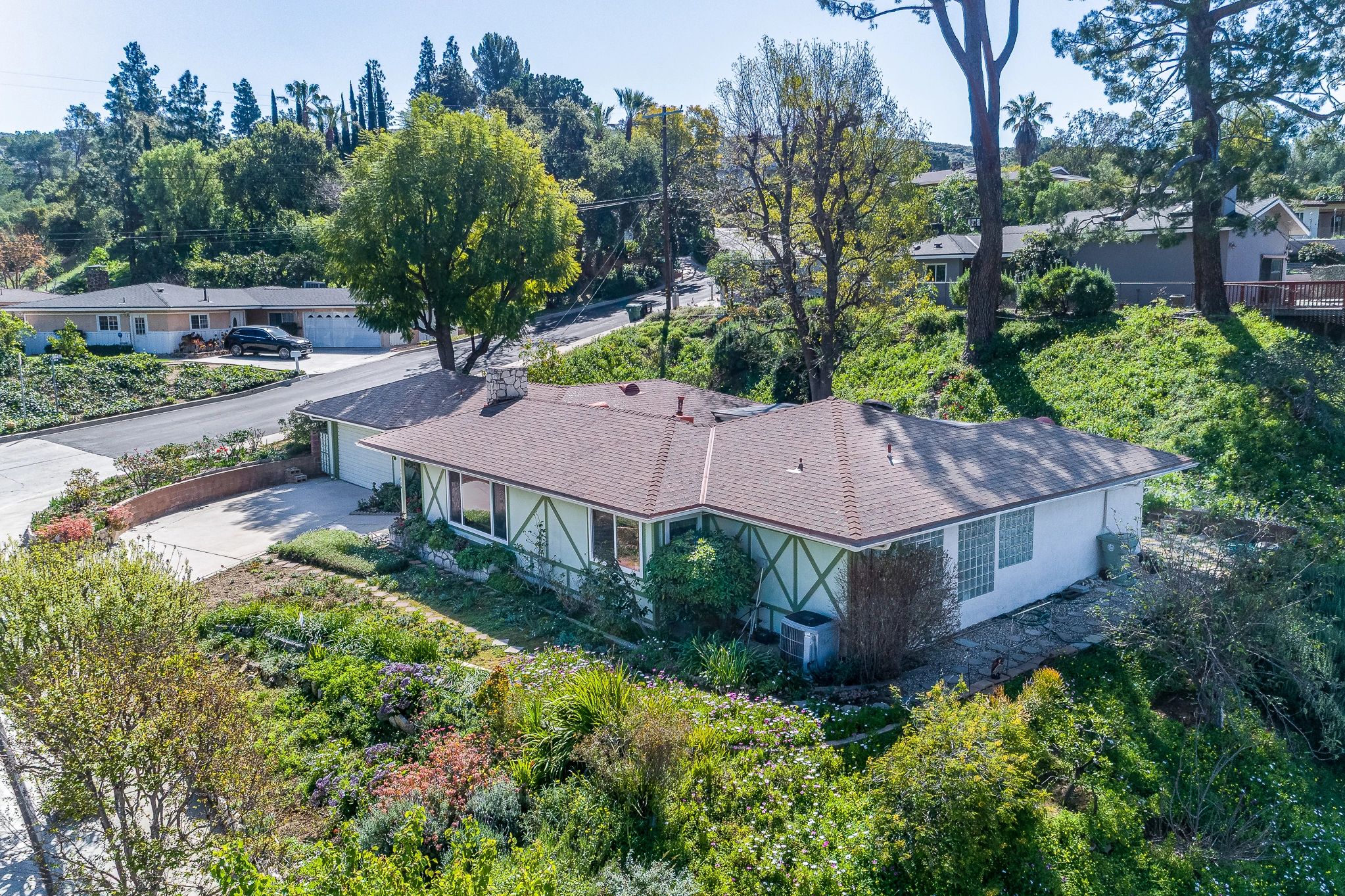 Suburban house surrounded by greenery and trees on a sunny day.