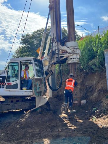 Construction workers operating heavy machinery at a worksite.