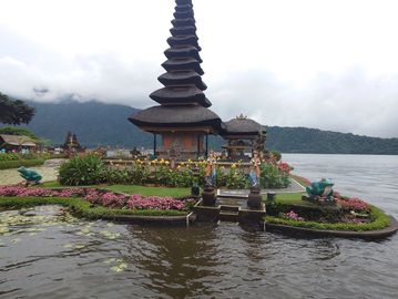 A traditional Balinese temple on a small island surrounded by water and mountains.