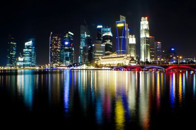City skyline at night with colorful reflections on water.