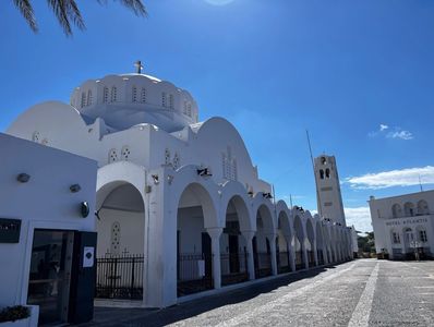 White church with arches and a domed roof under a clear blue sky.