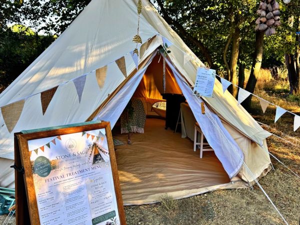 Outdoor festival tent with treatment menu board.
