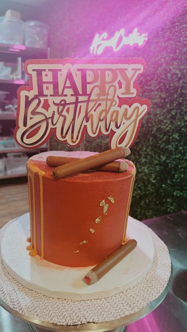Elegant brown birthday cake with cigar decorations.