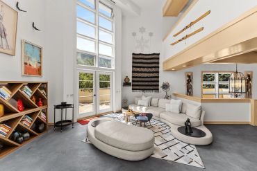 Modern living room with stylish furniture and large windows.