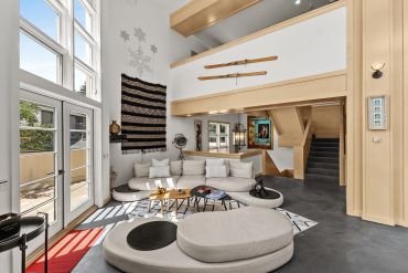 Modern living room with high ceilings and large windows.