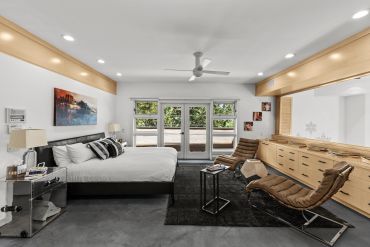 Modern bedroom with large mirror and seating area.