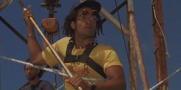 Man wearing a yellow t-shirt and glasses holding a rope on a boat.