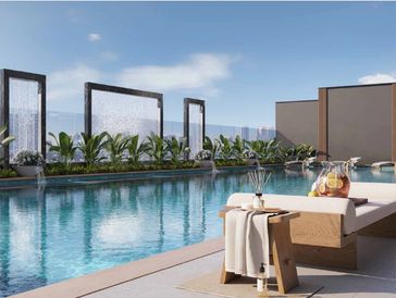 Sun loungers with iced tea pitcher on a table overlooking a swimming pool with Dubai Marina view