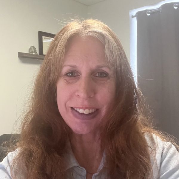 Smiling woman with long wavy hair indoors.