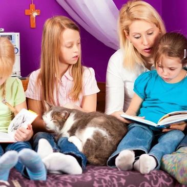 A woman and three children reading while a cat rests on their laps.