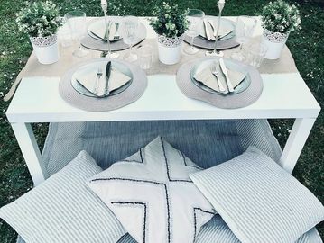 White table, with a rug and cushions on the floor to give a boho feel to an adult picnic