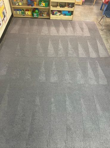 Carpet with triangle patterns created by vacuum cleaning in a classroom.