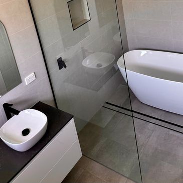 Modern bathroom with a white freestanding tub and black countertop sink.