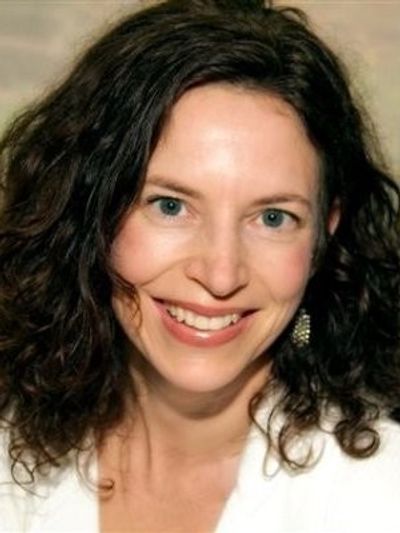 Smiling woman with curly hair and blue eyes.