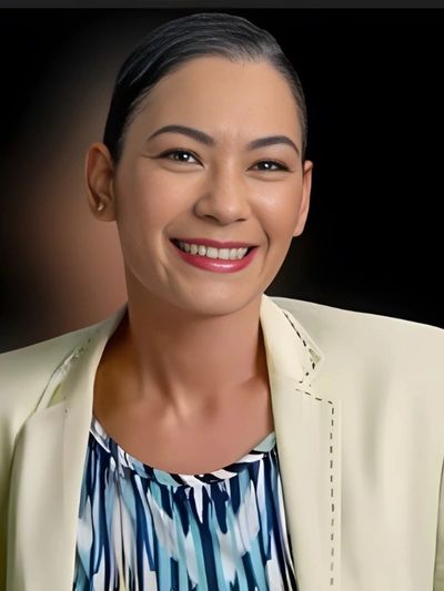 Professional woman smiling confidently in a light blazer and patterned blouse.