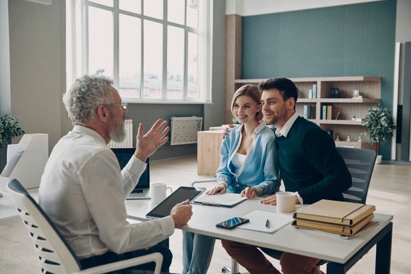 A medium shot shows three individuals in what appears to be an office or consultation room. 