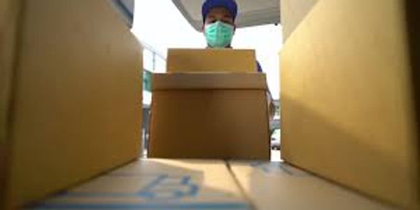 Person wearing a mask handling cardboard boxes.