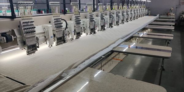 A long row of automated embroidery machines in a textile factory.