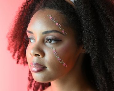 Young woman with floral face decorations looking contemplative.