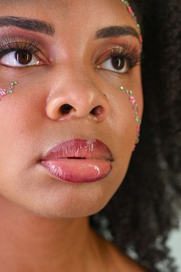 Close-up of a woman's face with floral face art and glossy lips.