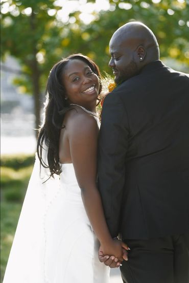 Happy couple holding hands outdoors on their wedding day.