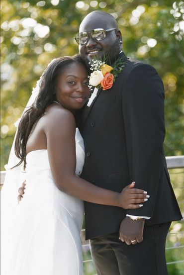 Bride and groom smiling and hugging outdoors.