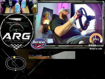 Man racing in a driving simulator with a progress bar for a 10k goal.