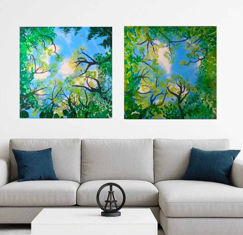 Two paintings over a couch depict the view skyward through a tree canopy of summer leaves
