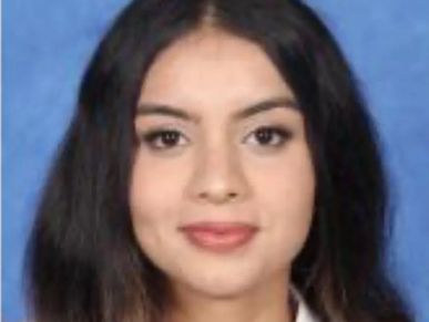 Portrait of a young woman with long dark hair against a blue background.