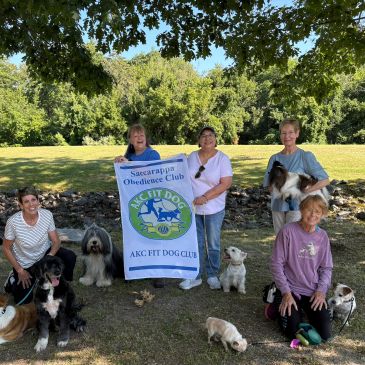 Group of people with dogs holding a Sacarappa Obedience Club banner.