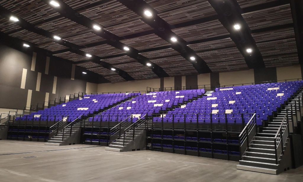 Empty indoor auditorium with purple seats and multiple staircases.