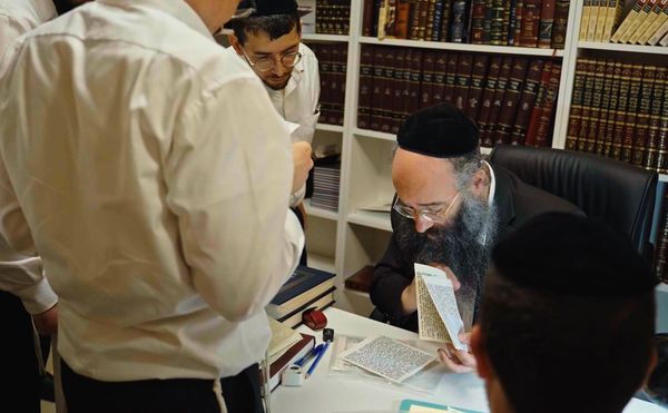 A group of men studying religious texts in a library setting.