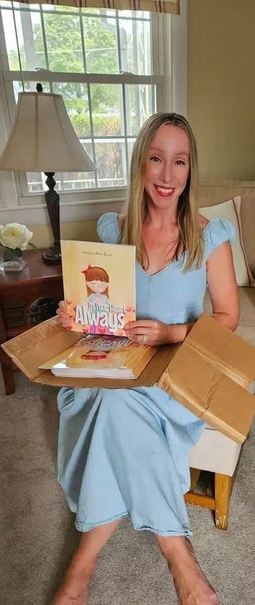 Woman holding a children's book titled "My Mama Loves Always."