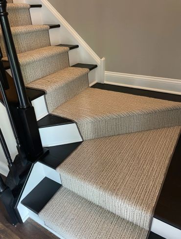 Carpeted stairs with a beige runner and black accents.