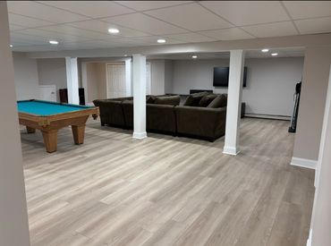 Spacious basement with a pool table and cozy sectional sofa.