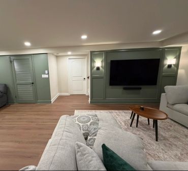 Modern living room with green accent walls, hardwood floors, and neutral-toned furniture.
