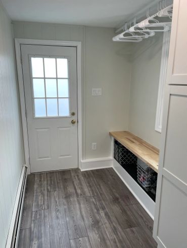 Bright mudroom with wooden bench and coat hangers.