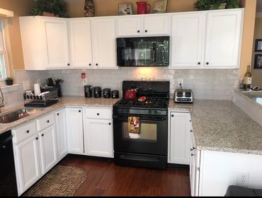 Modern kitchen with white cabinets, black appliances, and granite countertops.