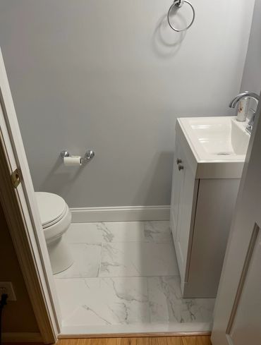 Small modern bathroom with white toilet and sink on marble floor.