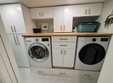 Modern laundry area with washing machine, dryer, and storage cabinets.