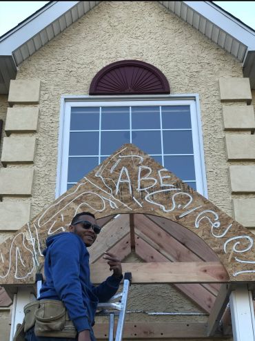 Man posing in front of a wooden arch with the word 'ABES' written on it.