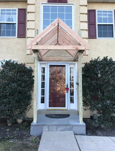 New wooden porch frame under construction at a house entrance.