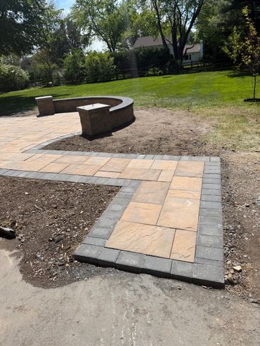 Newly installed patio with stone tiles and curved seating area in a backyard.