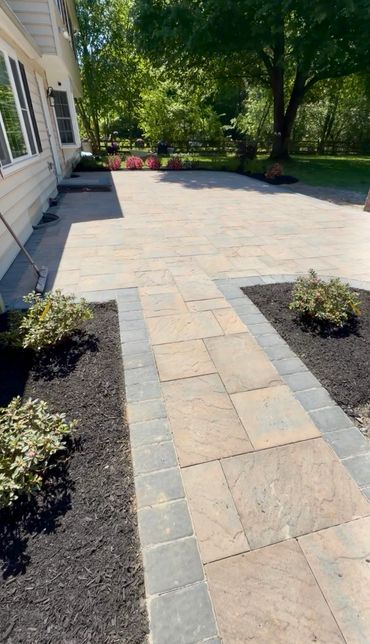 Spacious backyard patio with stone tiles and landscaped garden beds.