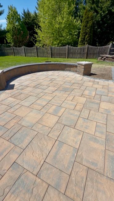 Spacious backyard patio with stone tiles and curved seating wall.