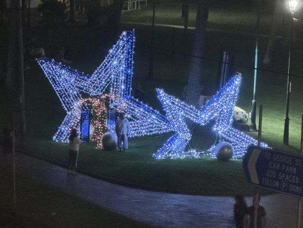 Blue star-shaped light decorations on a grassy area at night.